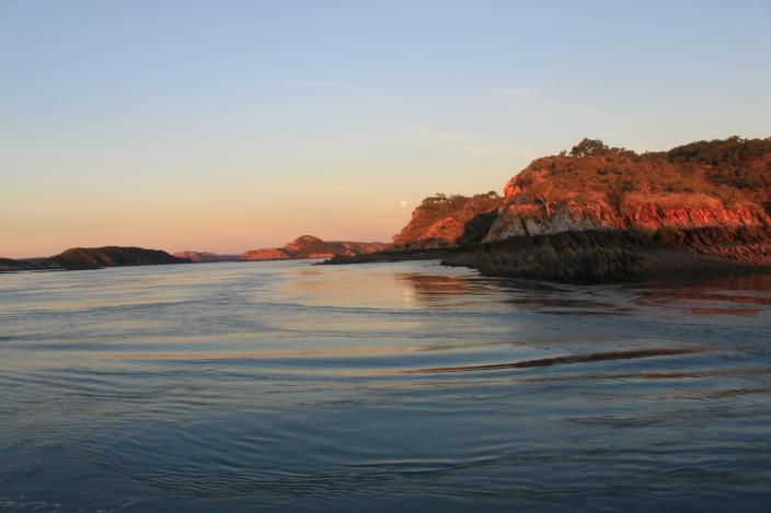 Image of a full moon rising over a bay